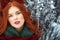 Beautiful red-haired young woman with perfect skin and make up posing on snowy and icy background