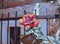 Beautiful red rose in the garden next to the old stone wall and black wrought iron lattice. Solar lighting. Flower garden in