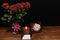 Beautiful red roses in vase with pink bow wrapped present and red candle with name tag on wooden table on dark background