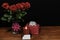 Beautiful red roses in vase with pink bow wrapped present and red candle with name tag on wooden table on dark background