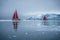 Beautiful red sailboat in the arctic next to a massive iceberg showing the scale. Cruising among floating icebergs in