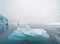 Beautiful red sailboat in the arctic next to a massive iceberg showing the scale. Cruising among floating icebergs in