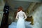 Beautiful redhair lady in elegant white wedding dress. Fashion portrait of model indoors. Beauty woman standing.