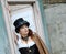 Beautiful redhair steampunk girl with goggles on black hat outside toilet background. Old-fashioned