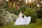 Beautiful redhead Bride in fantastic wedding dress in blooming garden.