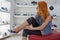 Beautiful redhead Caucasian girl choosing and wearing new shoes in the store