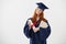 Beautiful redhead female graduate smiling holding books and diploma over white background.