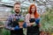 Beautiful redhead florist and an attractive gardener in his own flower greenhouse smiling large looking straight to the