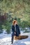 Beautiful redhead girl has a rest on the wooden log in winter