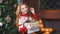 Beautiful redhead girl in red sweater holding Christmas gifts in hands.