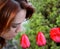 Beautiful redhead smelling tulips in a garden