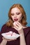 Beautiful redhead woman eats marshmallows.