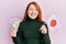 Beautiful redhead woman holding 5000 japanese yen banknotes and japan flag smiling and laughing hard out loud because funny crazy