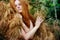 Beautiful redhead woman in a pine branch with dry needles