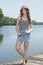 Beautiful redhead woman poses near water in denim skirt