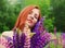 Beautiful redhead woman with vivid lupin bouquet in a field close-up