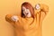 Beautiful redhead woman wearing casual winter sweater over yellow background stretching back, tired and relaxed, sleepy and