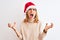 Beautiful redhead woman wearing christmas hat over  background crazy and mad shouting and yelling with aggressive