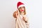 Beautiful redhead woman wearing christmas hat wearing pretend mustache over isolated background pointing with finger to the camera