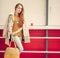 Beautiful redheaded girl with a fashionable bag in the hand is worth near the closed outdoor cafe