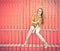 Beautiful redheaded girl in jeans sits near wall of red wooden planks