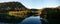 Beautiful reflections of blue sky, mountains and trees on creek