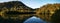 Beautiful reflections of blue sky, mountains and trees on creek