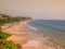 Beautiful and relaxing beach flanked by green palm trees at sunset. Varkala, Kerala, India.