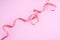 A beautiful ribbon on a gently pink background. Festive content. View from above, place for text