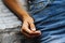 A beautiful ring on the finger of a young girl dressed in denim jeans and sitting on a stone wall