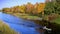 Beautiful river in autumn with a small boat, man and two dogs