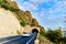 A beautiful road through the mountains. The cars enter the tunnel. Mountain ridges and a blue sky with clouds. on the right side