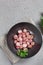 Beautiful roasted radishes in a black plate on concrete table, close up