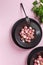 Beautiful roasted radishes in a black plate on pink table close up