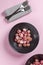 Beautiful roasted radishes in a black plate on pink table close up