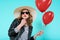 Beautiful rocker girl in leather jacket and summer hat kissing heart shaped popsicle and holding heart shaped balloons.