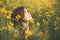 Beautiful romantic girl on blooming rapeseed field looking up, young woman walking, pretty female face, concert emotions,