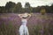 Beautiful romantic girl in a delicate dress with a hat sits in a flower field of purple lupine flowers. Soft selective focus