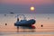 Beautiful romantic ocean sunrise at rimini beach italy; boat and ship in water at golden hour