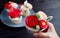 Beautiful rose bouquet frosting cupcake in woman`s hand with plate of blurry cupcakes in the backdrop