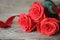 Beautiful roses in a bouguet of red, lying on a wooden table with red ribbon. Close-up.