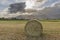Beautiful round hay bale in the Tuscan countryside, Italy, against a dramatic sky
