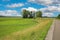 Beautiful rural countryside idyllic belgian landscape, vibrant strong green meadows, trees, bike cycle path, blue summer sky -