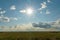 A beautiful rural field against a background of blue sky and clouds. Agro-industrial complex for the cultivation of cereals, wheat