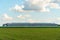 A beautiful rural field against a background of blue sky and clouds. Agro-industrial complex for the cultivation of cereals, wheat