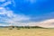 Beautiful rural landscape with a big blue sky over the hills and cropper and plowing vehicles