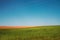 Beautiful rural landscape with on a green and brown plowed field on a background of blue sky