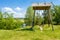 Beautiful rural landscape river Teteriv Teterev. On steep mountain face steeper swing - wooden structure with bench where child