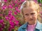 Beautiful sad blond little girl smelling flower and feeling upset. Kids pollen allergy. Sick child grimaces and sneezes