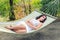 Beautiful sad girl in white dress lying in hammock